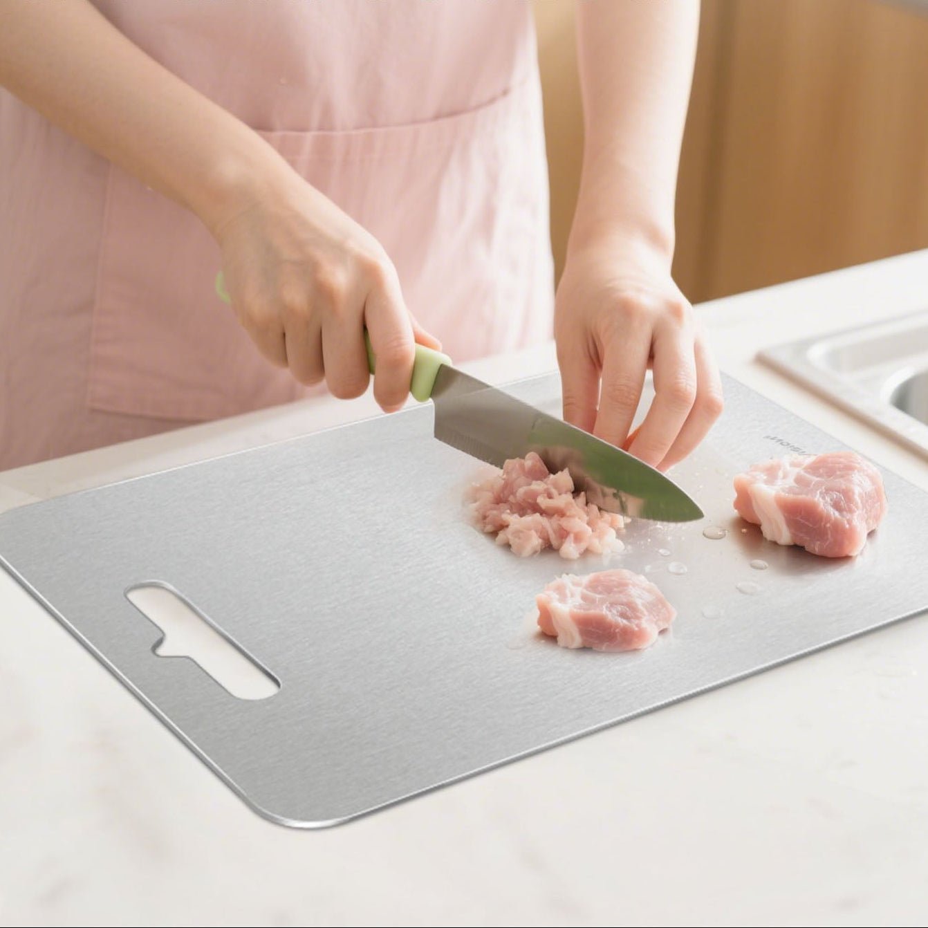 Femme coupe du poulet sur planche à découper en titane pur