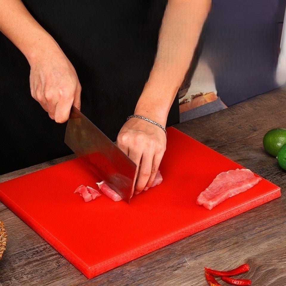 Homme coupe viande sur planche à découper professionnelle rouge