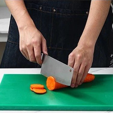 Homme coupe carotte sur planche à découper professionnelle verte