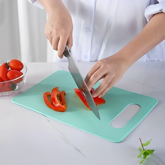 Chef coupe tomate sur planche a decouper verte