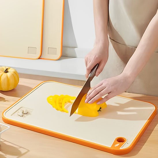 Femme coupe un légume sur une planche a decouper 