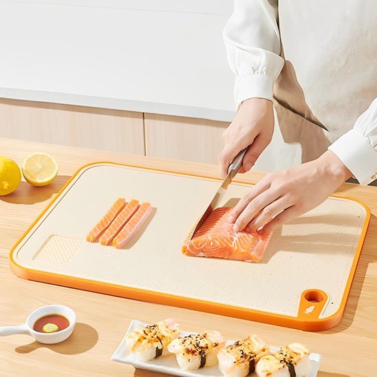 Femme coupe du poisson sur une planche a decouper en bioplastique.