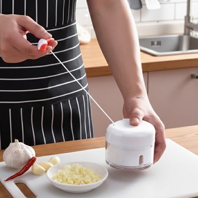cuisinier hache de l'ail avec un hachoir mini