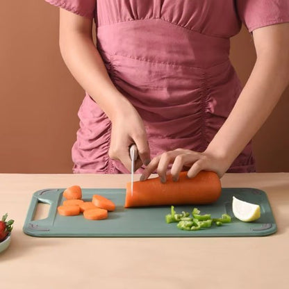 Femme coupe carotte sur planche a découper en inox réversible