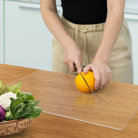 femme coupe fruit sur planche a découper transparente