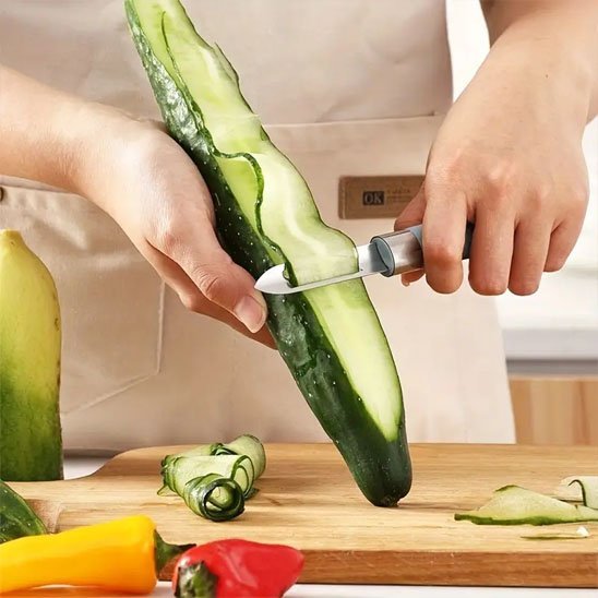 Femme fait des tranches minces de concombre avec Econome 