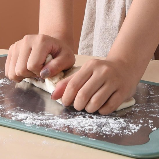 femme pétri pâte sur planche a découper en inox multi-usage