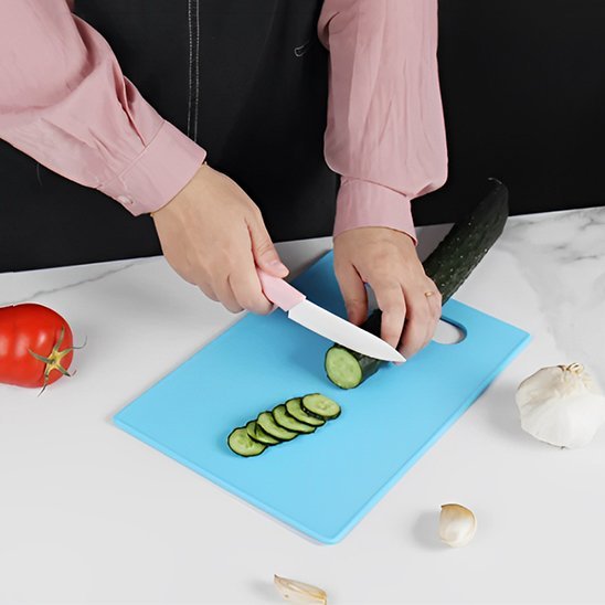 Femme tranche légume sur planche a decouper bleue