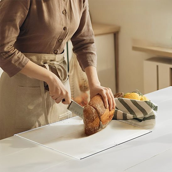 femme tranche pain sur planche a découper 