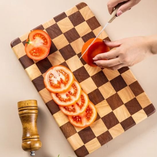 Femme tranche tomate sur planche à découper bois à motif de damier