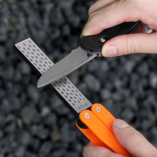 Homme aiguise petit couteau sur aiguiseur couteau de poche