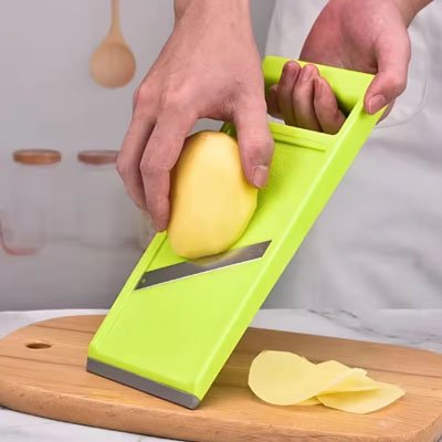 Homme coupe patates sur mandoline cuisine
