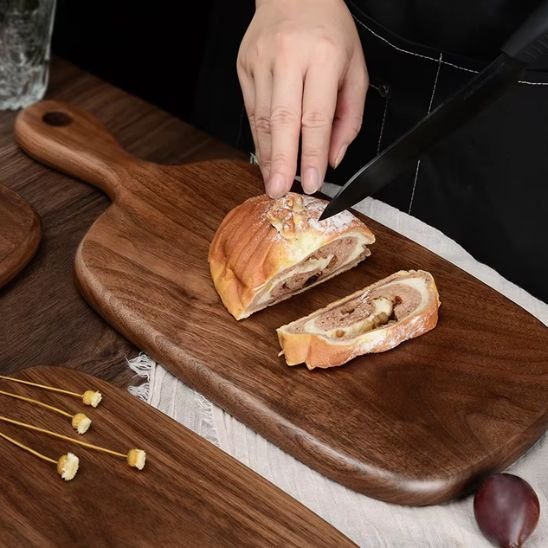 Homme coupe une patisserie sur planche bois à découper en noyer