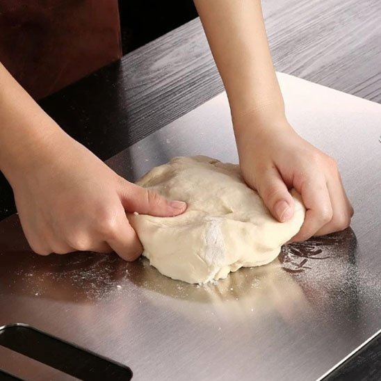 Homme pétri pâte sur planche à découper en inox