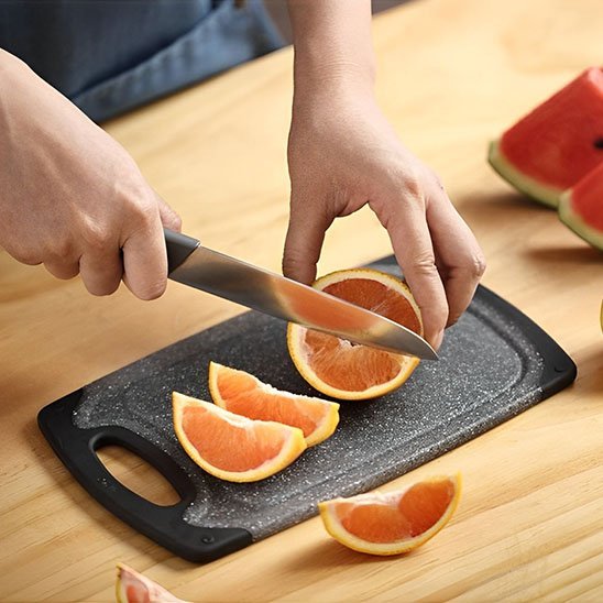 homme tranche orange sur planche à découper 