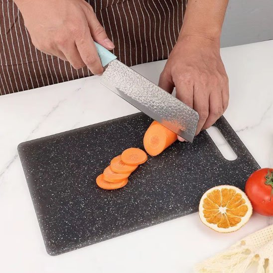 Homme coupe une carotte sur une planche a decouper noire