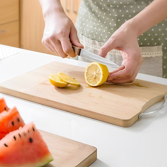 Femme tranche un citron sur une planche à découper bois